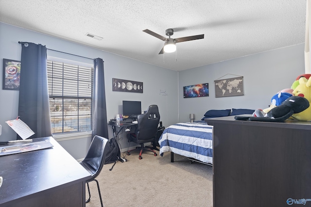 bedroom featuring a textured ceiling, light colored carpet, and ceiling fan