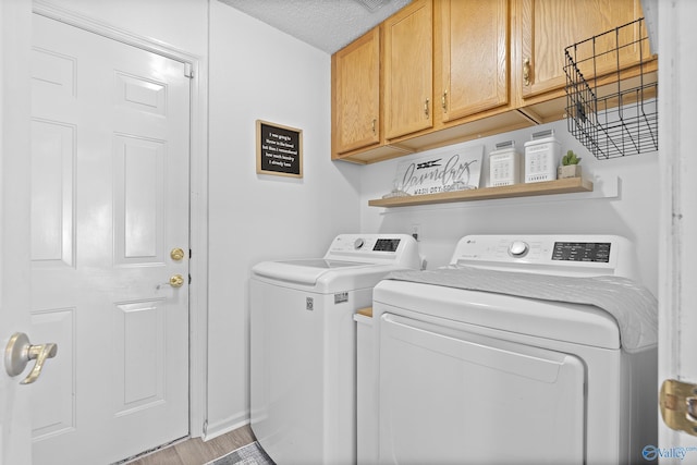 laundry room with washing machine and dryer, cabinets, and light wood-type flooring