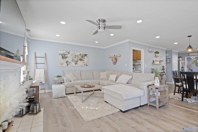 living room featuring ornamental molding, light wood-type flooring, ceiling fan, and a textured ceiling