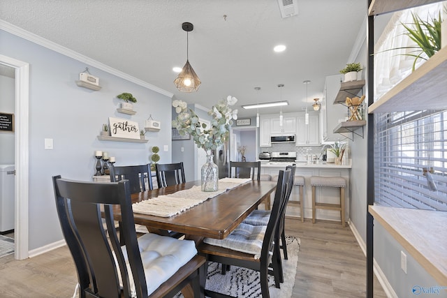 dining area featuring crown molding, a textured ceiling, and light wood-type flooring