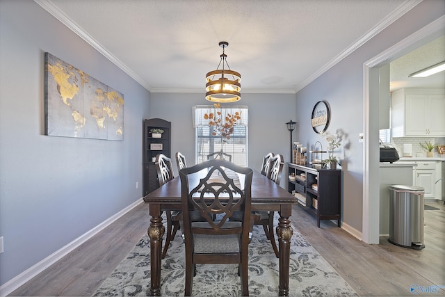 dining space featuring light hardwood / wood-style flooring, ornamental molding, and a textured ceiling