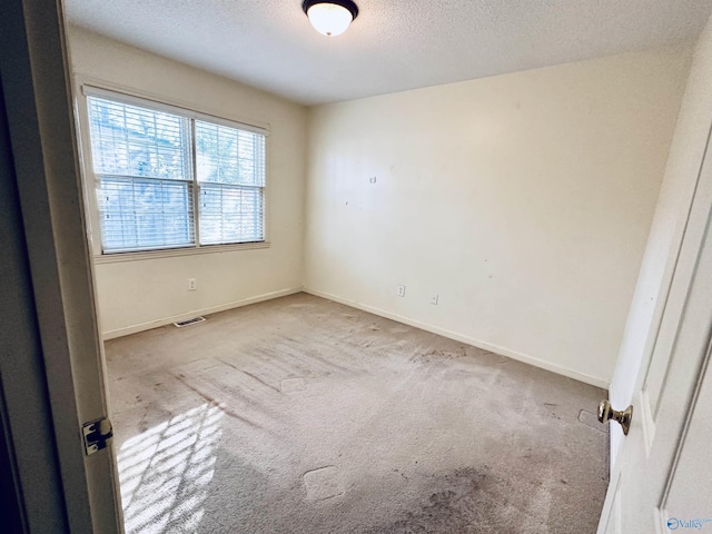 carpeted empty room with a textured ceiling