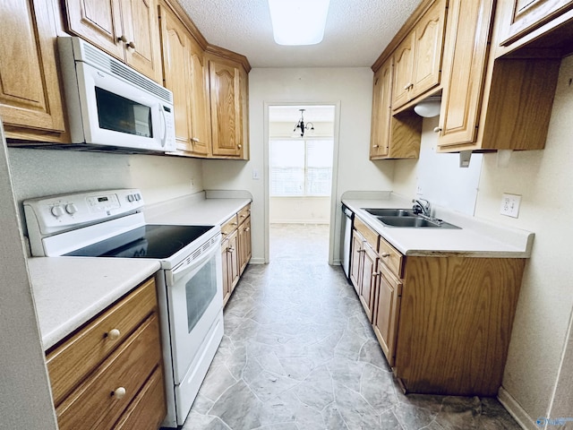 kitchen featuring a textured ceiling, sink, white appliances, and a notable chandelier