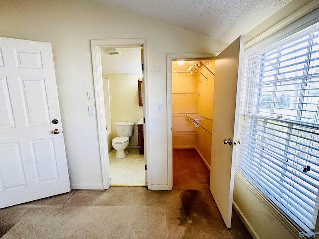 bathroom featuring a textured ceiling, toilet, and lofted ceiling