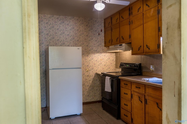 2808 Elmore Rd, Huntsville, AL 35805 - kitchen with freestanding refrigerator, black electric range, under cabinet range hood, light tile patterned floors, and brown cabinetry