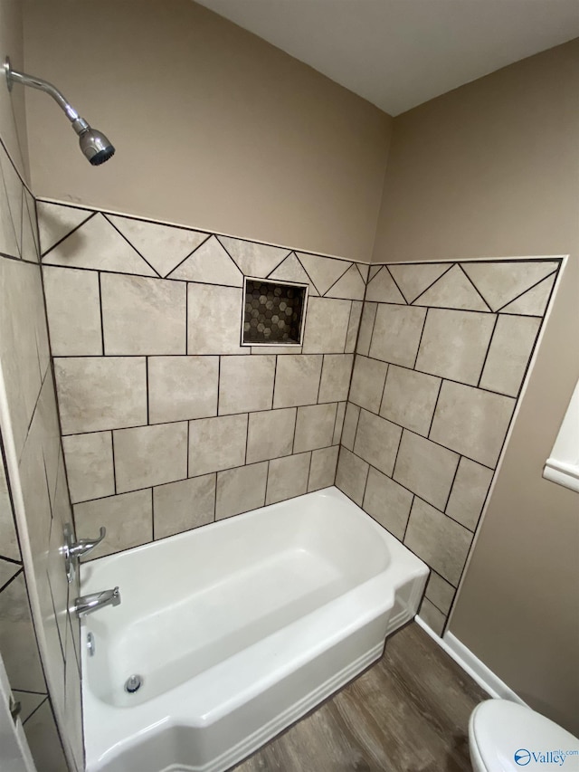 bathroom with hardwood / wood-style floors, tiled shower / bath combo, and toilet