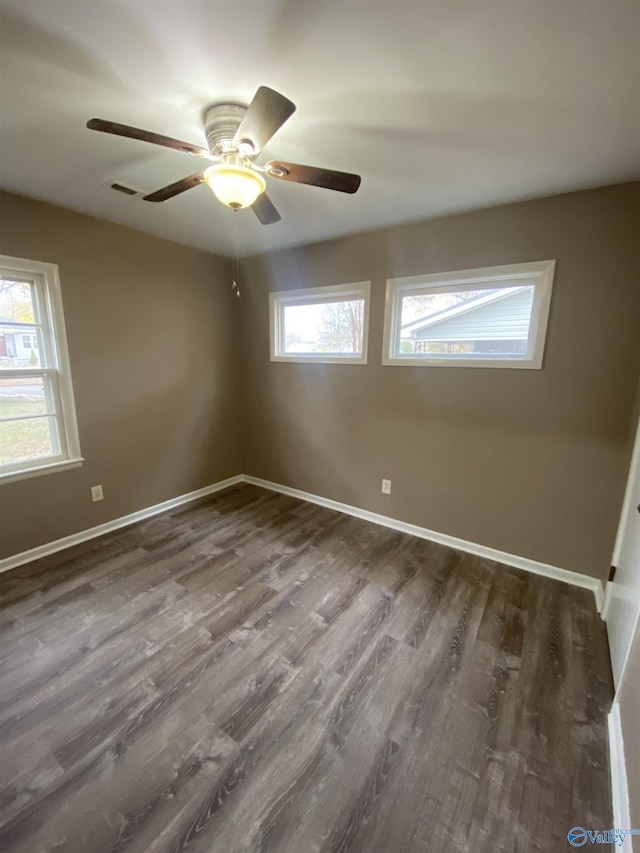 spare room with dark hardwood / wood-style flooring, ceiling fan, and a healthy amount of sunlight