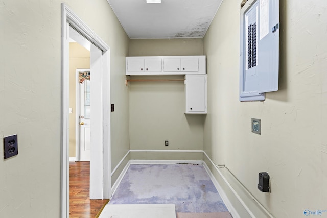 laundry area featuring electric panel and light hardwood / wood-style flooring