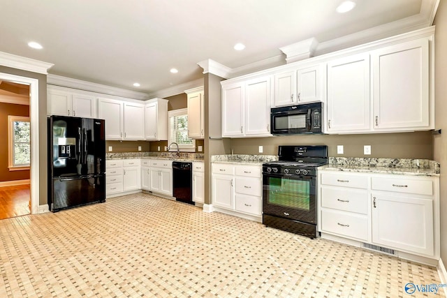 kitchen featuring a wealth of natural light, ornamental molding, black appliances, and white cabinetry