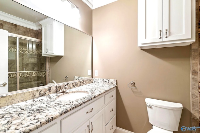 bathroom featuring vanity, toilet, ornamental molding, and a shower with shower door