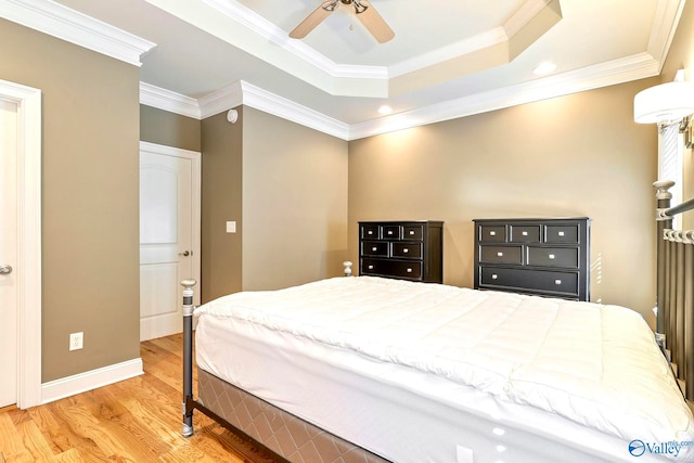 bedroom featuring hardwood / wood-style flooring, ensuite bath, crown molding, a raised ceiling, and ceiling fan