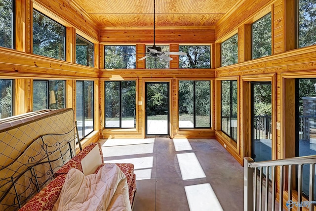 unfurnished sunroom featuring ceiling fan, a healthy amount of sunlight, and wooden ceiling