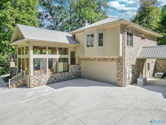 view of front of home with a sunroom, central AC, and a garage