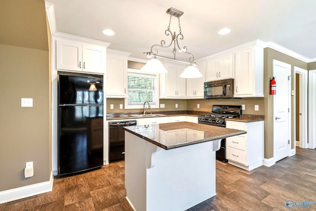 kitchen featuring a kitchen island, dark stone counters, sink, black appliances, and white cabinets