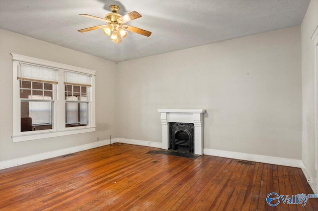 unfurnished living room with ceiling fan, a high end fireplace, hardwood / wood-style floors, and a textured ceiling