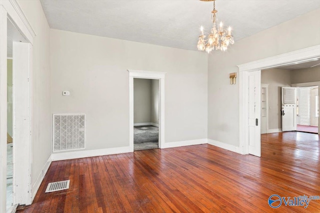 spare room with hardwood / wood-style flooring and a chandelier