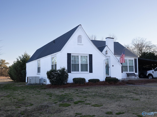 view of front of home featuring metal roof, central air condition unit, a carport, a chimney, and a front yard