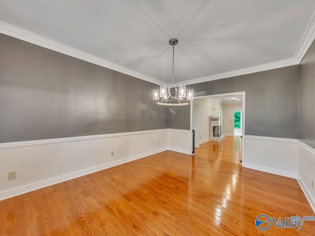 unfurnished dining area with baseboards, light wood-type flooring, ornamental molding, and an inviting chandelier