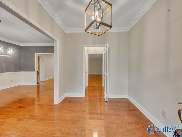 unfurnished dining area featuring crown molding, a notable chandelier, and light wood-style floors