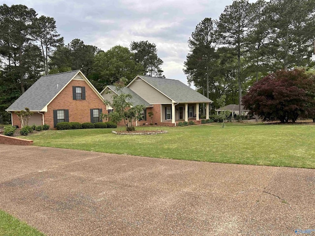 view of front facade with a front yard, covered porch, and brick siding