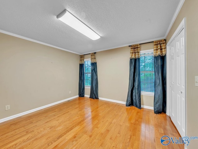 spare room featuring ornamental molding, a textured ceiling, and a healthy amount of sunlight