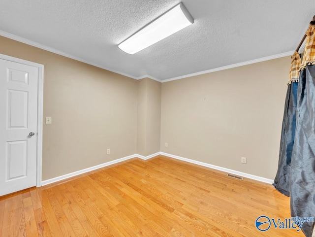 empty room featuring a textured ceiling, visible vents, light wood-style flooring, and baseboards