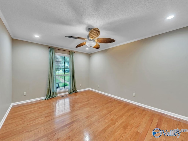 spare room featuring light wood finished floors, a textured ceiling, ceiling fan, and baseboards