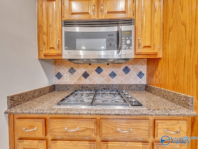 kitchen featuring stainless steel appliances, light stone countertops, and backsplash