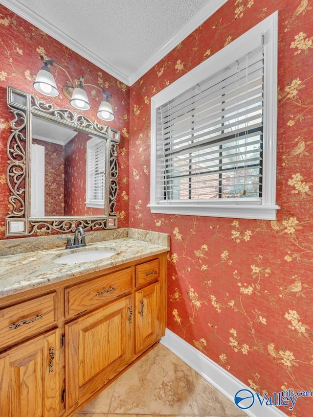 bathroom with a textured ceiling, vanity, ornamental molding, and baseboards
