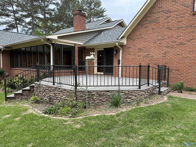 rear view of property featuring a patio, a chimney, a shingled roof, a yard, and brick siding