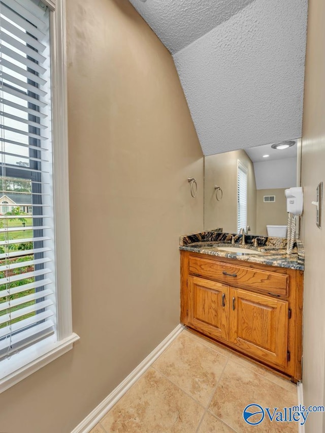 bathroom featuring tile patterned flooring, vanity, baseboards, visible vents, and a textured ceiling