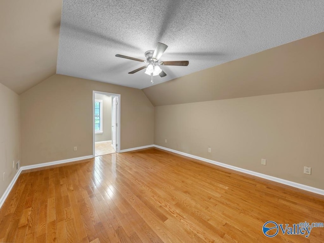 additional living space featuring light wood finished floors, a ceiling fan, lofted ceiling, and baseboards