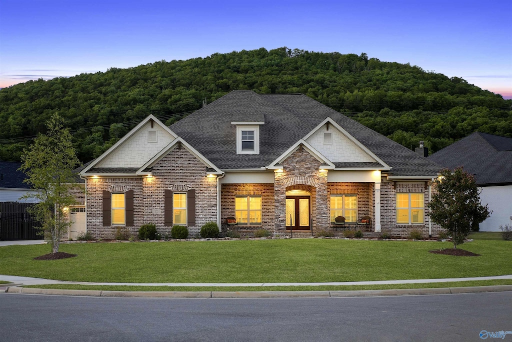 craftsman inspired home with a wooded view, a lawn, and roof with shingles