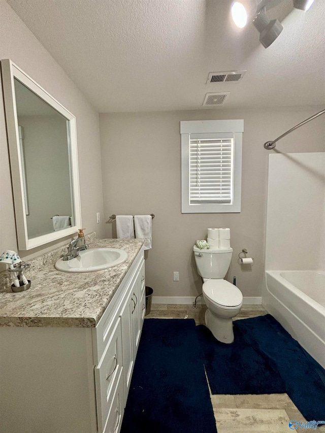 full bathroom with vanity, shower / tub combination, a textured ceiling, and toilet