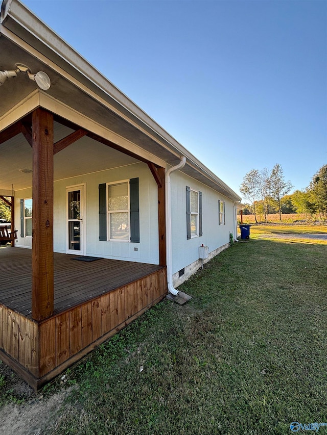 view of property exterior featuring covered porch and a lawn