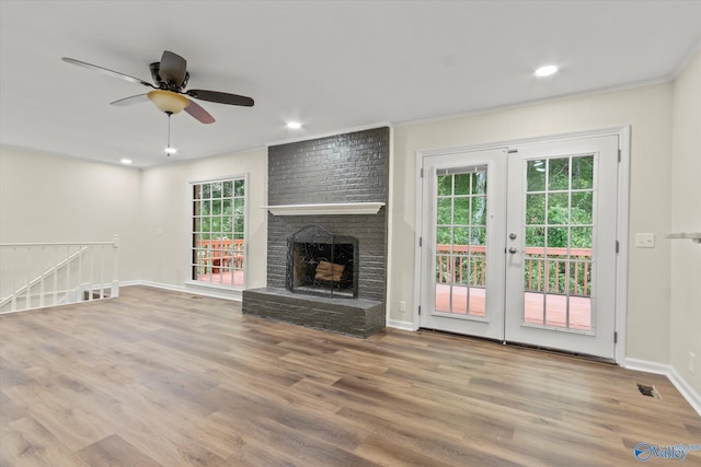 unfurnished living room featuring a brick fireplace, wood-type flooring, and ceiling fan