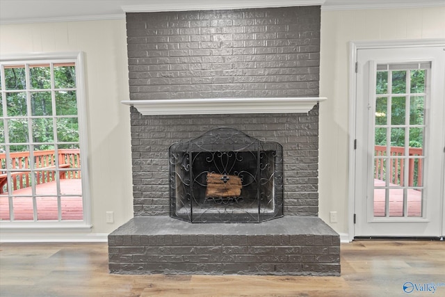 room details with crown molding, hardwood / wood-style flooring, and a brick fireplace