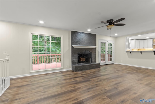 unfurnished living room featuring crown molding, dark wood-type flooring, ceiling fan, and a fireplace