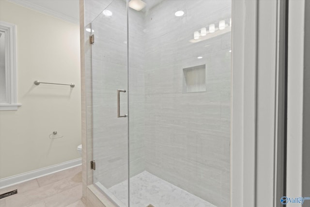 bathroom featuring crown molding, a shower with shower door, and toilet