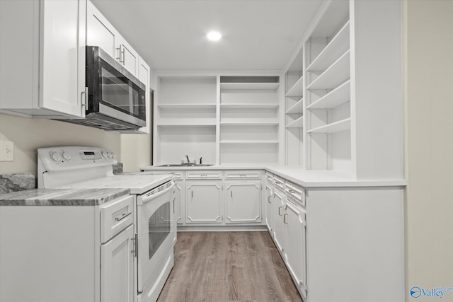 kitchen with electric range, sink, hardwood / wood-style flooring, and white cabinets