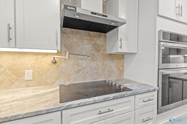 kitchen featuring black electric stovetop, backsplash, light stone countertops, double oven, and white cabinets