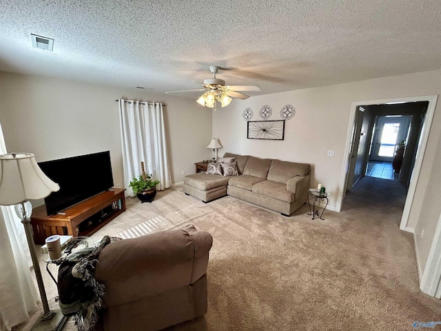 carpeted living room with ceiling fan and a textured ceiling