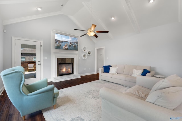 living area with ceiling fan, a tile fireplace, wood finished floors, baseboards, and vaulted ceiling with beams