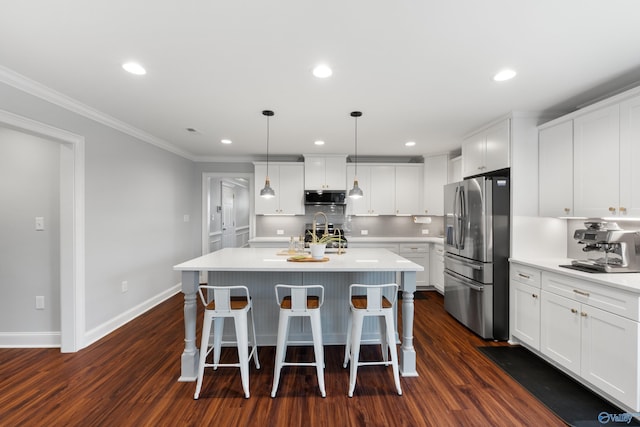 kitchen featuring backsplash, appliances with stainless steel finishes, light countertops, ornamental molding, and dark wood-type flooring
