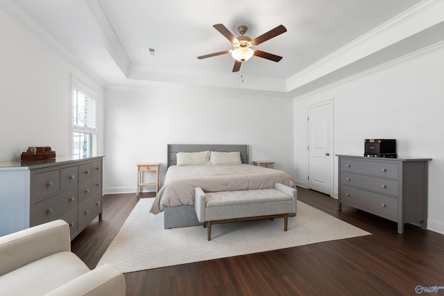 bedroom with ornamental molding, dark wood-style flooring, baseboards, ceiling fan, and a tray ceiling