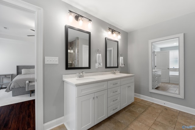 ensuite bathroom with a sink, baseboards, double vanity, and connected bathroom