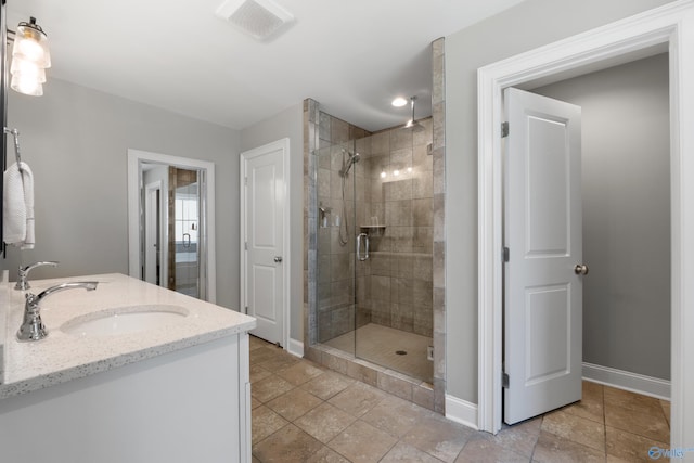 full bathroom with visible vents, double vanity, baseboards, a shower stall, and a sink