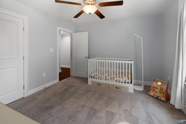unfurnished bedroom with baseboards, a ceiling fan, carpet, and a nursery area
