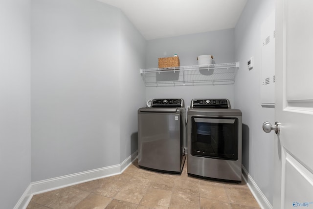 washroom featuring laundry area, washer and clothes dryer, baseboards, and stone finish floor