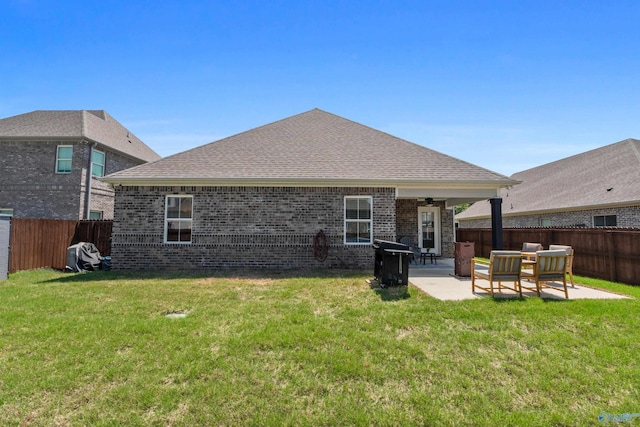 back of property with brick siding, ceiling fan, a fenced backyard, a patio area, and a lawn
